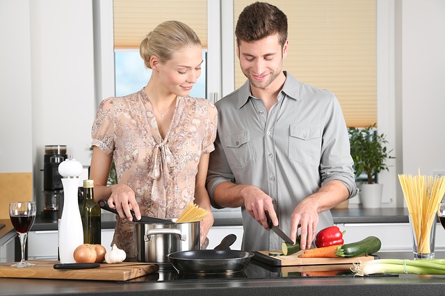 Couple cuisinant ensemble dans la joie et la bonne humeur.